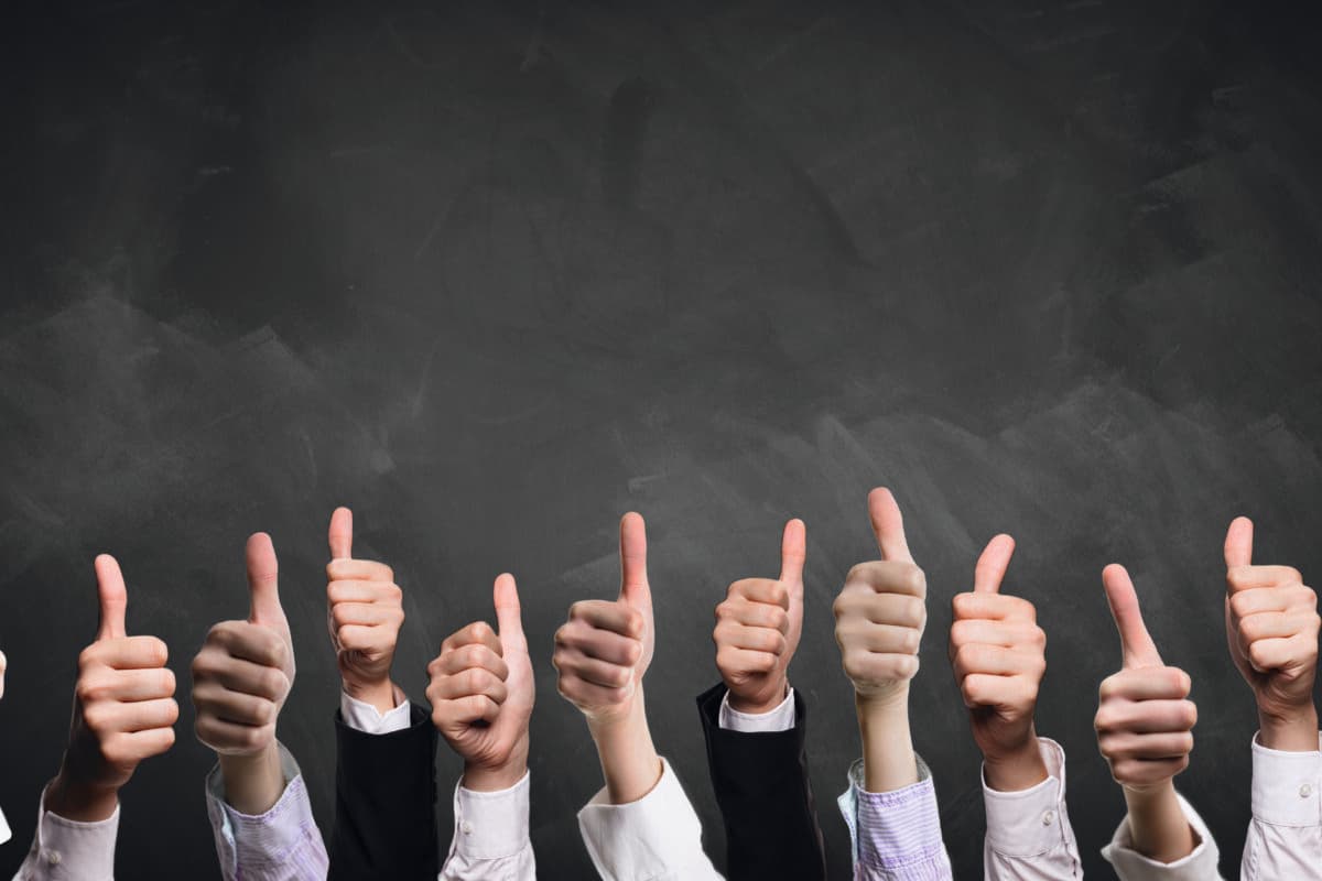 many thumbs up in front of a blackboard